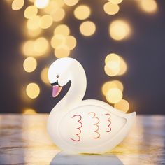 a white swan figurine sitting on top of a table with lights in the background