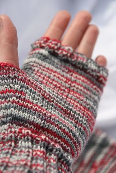 a person's hand wearing a red, grey and white knitted mitt