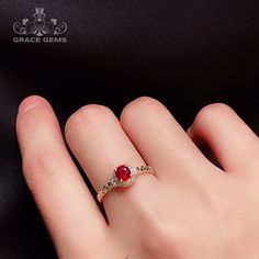 a woman's hand with a red and white diamond ring on top of it