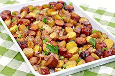 a square white dish filled with roasted potatoes and garnished with parsley on a checkered tablecloth