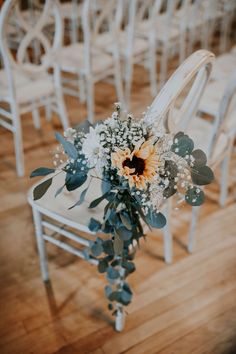 a bouquet of flowers sitting on top of a white chair in front of rows of chairs