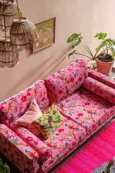 a living room with a pink couch and potted plants