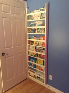 a book shelf in the corner of a room next to a door with books on it