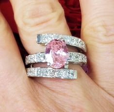 a woman's hand with two rings and a pink diamond in the middle, on top of her finger