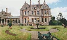 an old house with a circular garden in the front yard and lawn furniture around it