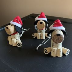 three wooden dogs wearing santa hats on top of a black table next to each other