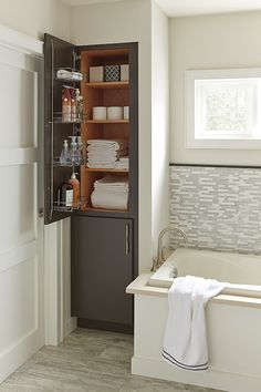 a bathroom with a bathtub, cabinet and towels