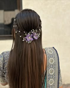 the back of a woman's head with long hair and flowers in her hair