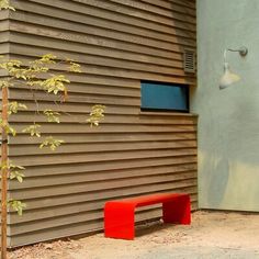 a red bench sitting in front of a building next to a tree and lamp post