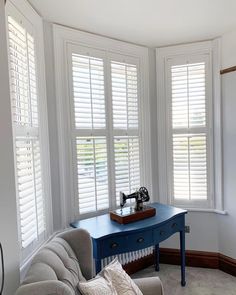 a living room filled with furniture and windows covered in white shuttered glass coverings