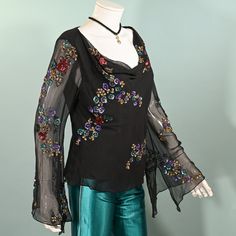 Vintage sheer black silk angel sleeve blouse with sequin & beaded flowers.  Cowl neckline, pullover top. Relaxed fit at the waist.  SIZE:  All sizing given is approximate. Refer to measurements for an accurate fit. Shoulder: 17" Underarm: 42" Sleeve: 24 3/4" Waist: 37" Length: 21" Mannequin measurements:   Size 2, Bust - 33"   Waist - 24"   Hips - 34" CONDITION:  Very good COLOR: Black, multicolored sequins & beads.  MATERIAL: silk chiffon, sequins, beads.  CARE: Dry clean.  We try to give very accurate descriptions for each item. We are a smoke-free environment. Domestic Shipping: Priority Mail including free tracking and insurance. Upon request - International Shipping: First Class including tracking & insurance as available. FINAL SALE. Accessories not included in the sale, they are for Spring Embellished Silk Tops, Glamorous Long Sleeve Silk Tops, Festive Long Sleeve Embellished Tops, Festive Long Sleeve Evening Tops, Fitted Silk Embellished Tops, Silk Long Sleeve Embellished Blouse, Silk Embellished Party Top, Embellished Silk Tops For Night Out, Embellished Silk V-neck Top