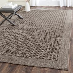 a large rug in the middle of a living room with a chair and vase on it