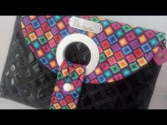 a colorful purse with a white ring on the front and black bottom, decorated with multicolored squares