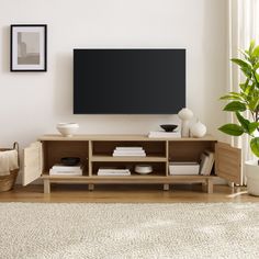 a living room with a large flat screen tv mounted on the wall above a wooden entertainment center