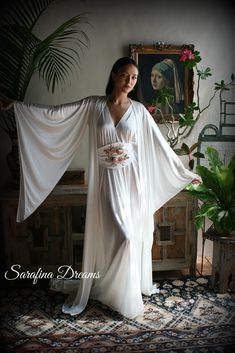 White satin Bridal robe from our newest collection. Our satin is a stretch poly nylon that is the softest you'll find both inside and out so the fabric next to the skin is slinky and very silky. This is a match to our angel wing gown and is graced with long pointed wing sleeves. A classic kimono style that we've added a train to which adds a touch of glam and romance. Two side inseam pockets and it will come with a self fabric tie sash belt to close. It is shown with the angel wing gown which is Kimono Wedding Dress, Winged Sleeves, Wedding Sleepwear, Moda Kimono, Satin Bridal Robe, Vintage Loungewear, Night Gown Dress, Bridal Nightgown, Robe Wedding