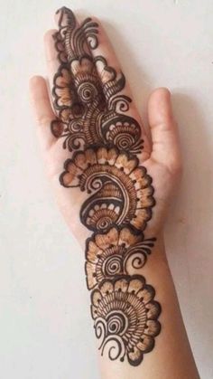 a woman's hand with henna tattoos on her arm and the bottom half of it