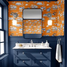 a bathroom with orange and blue wallpaper, white counter tops and two sinks under a large mirror