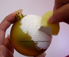 someone is decorating a christmas ornament with white and yellow powder on it