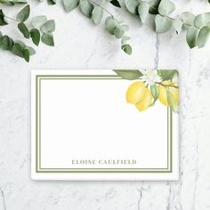 a place card with lemons and green leaves on a marble surface, surrounded by greenery