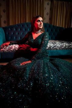 a woman sitting on top of a blue couch in a black and red dress with sequins