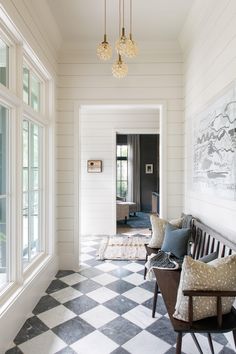 a hallway with checkered floor and chandelier hanging from it's ceiling