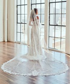 a woman in a white wedding dress standing on a wooden floor with her veil pulled back