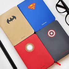 four different colored notebooks sitting on top of each other next to a pair of glasses