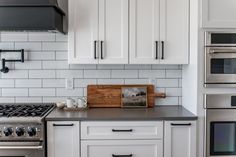 a kitchen with white cabinets and stainless steel appliances, including an oven, microwave, toaster and coffee maker