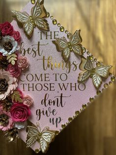 a pink graduation cap decorated with gold butterflies and flowers that says the best things come to those who don't give up