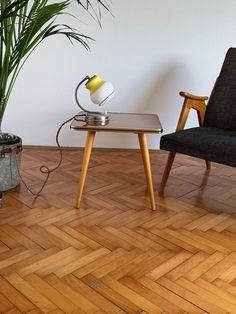 a table with a lamp on it next to a chair and a potted plant