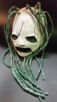 a white mask with long green cords on it's face and eyes, sitting on top of a table