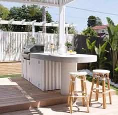 an outdoor kitchen with two stools on the deck