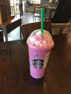 a pink starbucks drink sitting on top of a wooden table