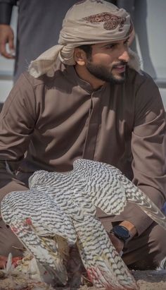 a man sitting on the ground with an owl