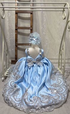 a doll sitting on top of a chair wearing a blue dress