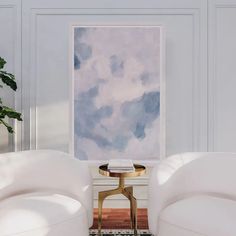 a living room with two white couches and a painting on the wall