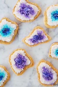 some cookies with blue and purple icing on them sitting on a marble counter top