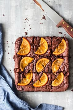 a brownie with orange slices on it next to a knife