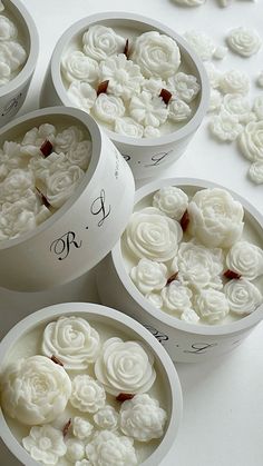 four white bowls with flowers in them sitting on a table