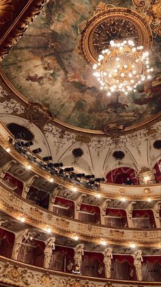 an ornately decorated auditorium with chandelier and painted ceiling, looking up at the stage