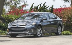 a gray toyota camry parked in front of some bushes