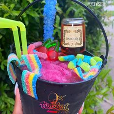 a bucket filled with candy, jelly and gummy bears next to a jar of honey