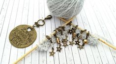 a ball of yarn and some knitting needles on a white wooden table with a gold keychain