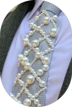 a close up of a tie with pearls on it and a button down shirt in the background