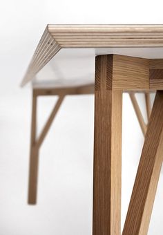 a close up of a wooden table with a white top and wood legs on it