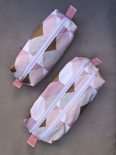 two pink and white bags sitting on top of a gray floor next to each other