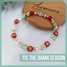 a bracelet with the words'tis the damn season'written in gold and red beads