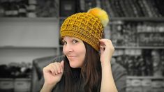 a woman wearing a yellow knitted hat with pom - poms