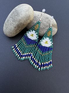 a pair of beaded earrings sitting on top of a rock