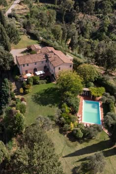 an aerial view of a house with a swimming pool in the middle of trees and grass